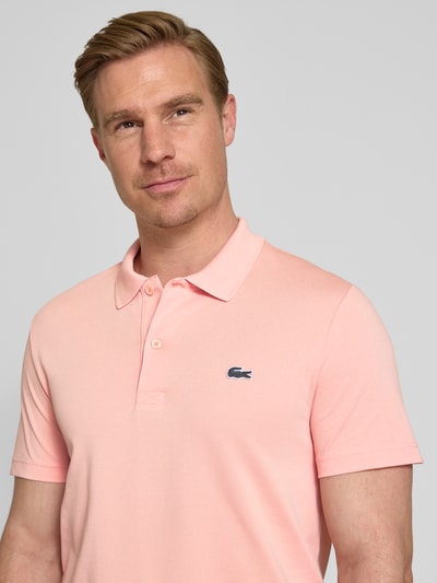 Männermodel trägt Regular Fit Poloshirt aus Baumwoll-Mix von Lacoste, Optik: Unifarben, Logo-Patch, Polokragen, Kurzarm, Nahaufnahme Oberkörper.