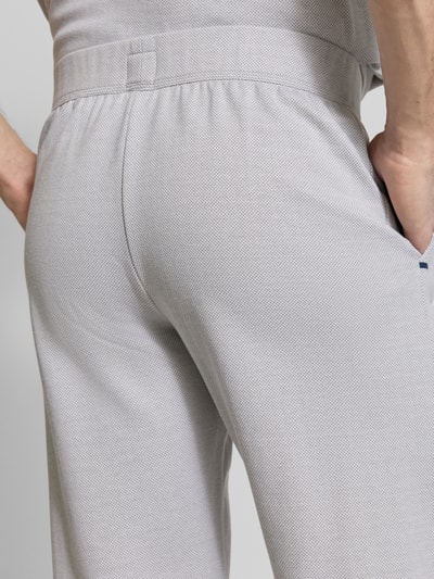 Männermodel trägt Sweatpants mit elastischem Bund von Schiesser in Grau, fein strukturiert, Relaxed Fit, Detailaufnahme Rückansicht.