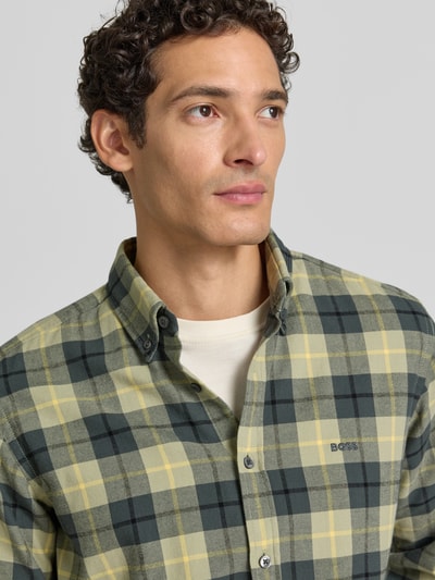 Männermodel trägt Regular Fit Freizeithemd aus reiner Baumwolle Modell 'Rickert_M' von BOSS Orange in Gelb-Grün-Karo, Nahaufnahme Oberkörper.