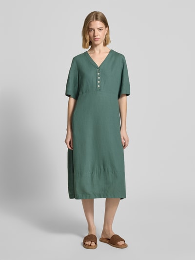 Frauenmodel trägt knielanges Kleid aus Leinen-Viskose-Mix Modell 'Lava' von FREE/QUENT in A-Linie, V-Ausschnitt, Knopfleiste, smaragdgrün, glatte Textur, Ganzkörperansicht von vorne. Im Kontext: Damen Kleid, Brustweite 43 cm, Rückenlänge 96 cm, Ärmellänge 29 cm.