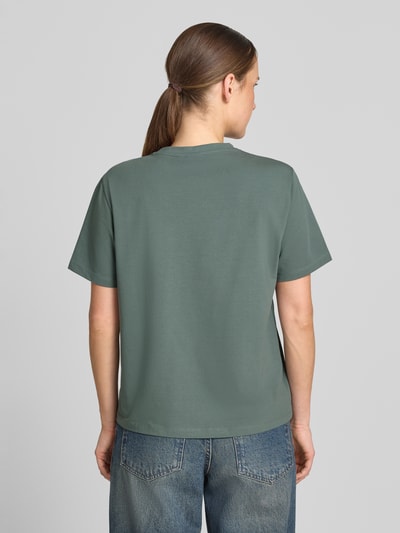 Frauenmodel trägt T-Shirt mit Rundhalsausschnitt Modell 'NORA' von VILA aus Baumwoll-Elasthan-Mix in Regular-Fit, Rückenlänge 60 cm, einfarbig, glatte Textur, Ganzkörperansicht Rückansicht.
