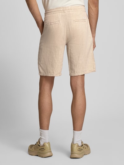 Männermodel trägt Shorts aus Leinen-Mix mit Eingrifftaschen Modell 'MARCO' von Blend in Beige, Straight Fit, Ganzkörperansicht Rückansicht.