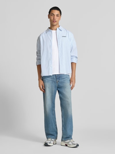 Męski model nosi Regular Fit T-Shirt aus Baumwoll-Mix von JACK & JONES, mieszanka bawełny, krój regular fit, okrągły dekolt, z krótkim rękawem, długość tyłu w rozmiarze M: 67 cm, jasne kolory, proste kształty, gładka tekstura, całopostaciowy widok z przodu.