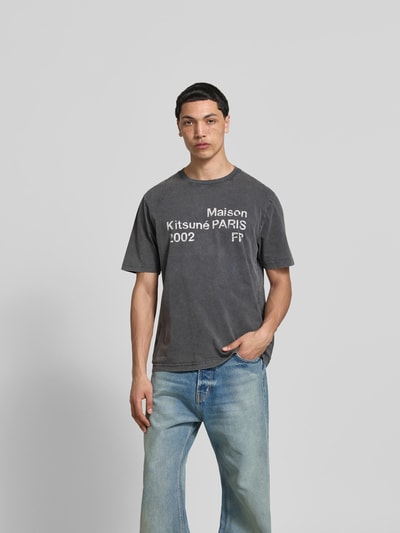 Männermodel trägt Relaxed Fit T-Shirt mit Logo-Print von MAISON KITSUNÉ aus reiner Baumwolle, Rundhalsausschnitt, kurzärmelig, Ganzkörperansicht von vorne.