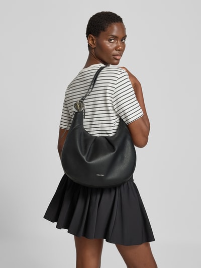 Vrouwenmodel draagt zwarte Henkeltasche met labeldetail van CK Calvin Klein, effen structuur, Dames, Ganzkörperaanzicht rugaanzicht
