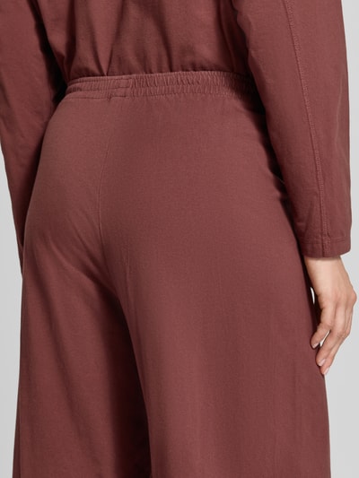 Frauenmodel trägt Wide Fit Hose aus reiner Baumwolle Modell 'GIXY' von American Vintage in Braun mit elastischem Bund, Detailaufnahme, Damen Hose von American Vintage, reine Baumwolle, Wide Fit, elastischer Bund, Bundweite Größe S 34 cm, Innenbeinlänge 37 cm.