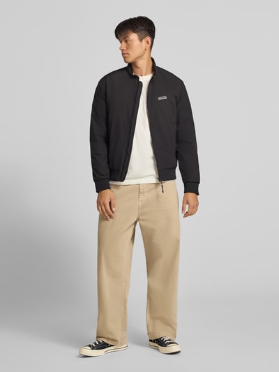 Männermodel trägt zwarte Bomberjacke met Logo Modell 'BROOKLYN' van JACK & JONES, regular fit, opstaande kraag, ritssluiting, heren, Ruglengte maat M: 67 cm, schouderbreedte: 49 cm, borstwijdte: 59 cm, mouwlengte: 66 cm, Ganzkörperansicht van voren.