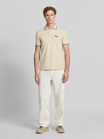 Męski model nosi Regular Fit Poloshirt aus Baumwoll-Mix Modell 'PADDY PRO' von BOSS Green w kolorze beżowym, gładka faktura, Ganzkörperansicht von vorne.