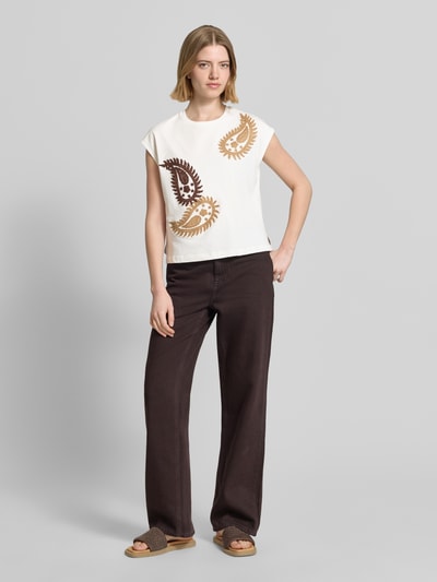 Frauenmodel trägt T-Shirt mit Rundhalsausschnitt und Stitchings Modell 'RICAMO' von Stefanel, weiße Baumwolle, Regular Fit, braune Muster, Ganzkörperansicht von vorne.