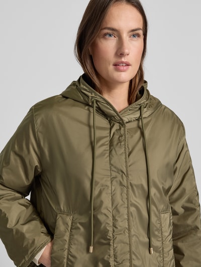 Młodzieżowy model nosi Relaxed Fit Funktionsjacke mit Woll-Füllung Modell 'AGRESTE' od Weekend Max Mara w kolorze oliwkowym, matowa tekstura, logo-patch na ramieniu, boczne kieszenie, kaptur, zdjęcie: zbliżenie na górną część ciała.