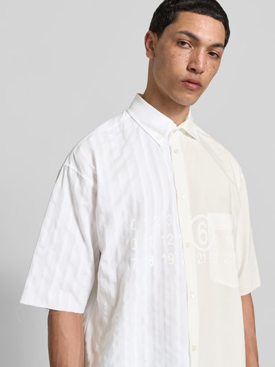 Männermodel trägt Regular Fit Freizeithemd aus Reine Baumwolle von MM6 Maison Margiela im Asymmetrischer-Look, Halbarm, Nahaufnahme Oberkörper.