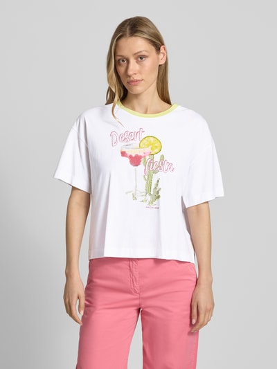 Modelka kobieca ma na sobie T-Shirt mit Motiv-Print und Rundhalsausschnitt od Marc Cain, boxy fit, czysta bawełna, motyw, cekiny, biała i różowa kolorystyka, długość tyłu w rozmiarze 36: 53 cm, całkowity widok z przodu
