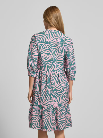 Frauenmodel trägt Relaxed Fit Midikleid aus Viskose-Mix mit Tunika-Ausschnitt von Christian Berg Woman, abstraktes Muster in Rosa und Grün, Knopfleiste, Halbarm, Rückenlänge bei Größe 36: 106 cm, Brustweite: 48 cm, Ärmellänge: 45 cm, Ganzkörperansicht Rückansicht.