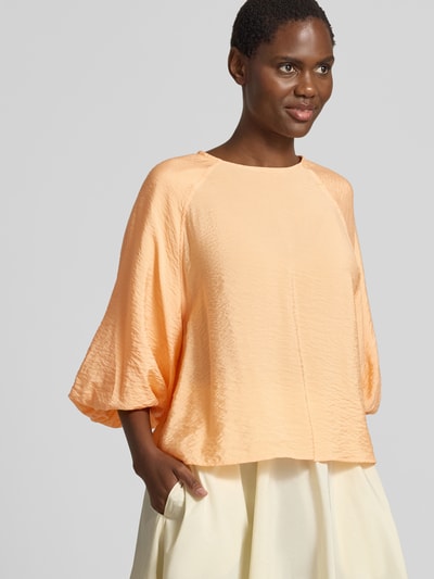 Frauenmodel trägt Regular Fit Bluse aus Viskose-Mix mit 3/4-Arm von Christian Berg Woman in Pfirsich, Rundhalsausschnitt, Ganzkörperansicht von vorne. Rückenlänge bei Größe 36: 56 cm, Ärmellänge bei Größe 36: 44 cm.