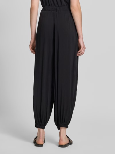 Frauenmodel trägt Relaxed Fit Jogginghose aus reiner Viskose Modell 'Radia' von Soyaconcept, schwarz, elastischer Bund, Rückansicht Ganzkörperansicht.
