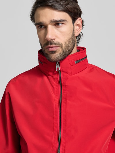 Männermodel trägt Regular Fit Jacke mit Kapuze Modell 'Como' von NAUTGÅRD in Rot, glatte Struktur, Nahaufnahme Oberkörper. Jacke mit Stehkragen, Zweiwegereißverschluss, elastischen Abschlüssen und Reißverschlusstaschen, Rückenlänge ca. 67 cm, Schulterbreite 48 cm, Brustweite 60 cm, Ärmellänge 67 cm.