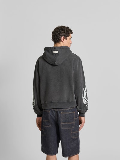 Männermodel trägt Oversized Sweatjacke aus Baumwolle von Don´t Waste Culture, dunkle Farbe, Rückenansicht, strukturierte Oberfläche, Ganzkörperansicht Rückansicht.