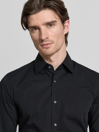 Männermodel trägt schwarzes Slim Fit Businesshemd mit extra langem Arm von BOSS, glatte Baumwoll-Popeline, Nahaufnahme Oberkörper.