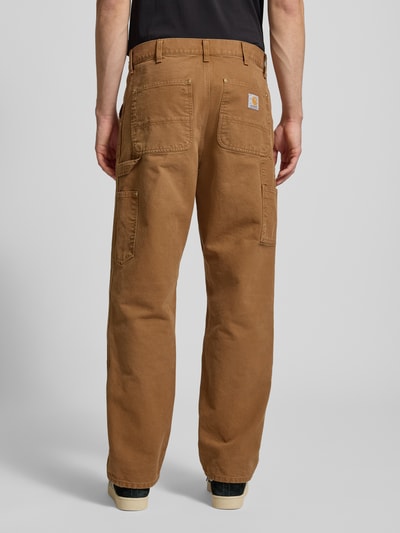 Męski model nosi Spodnie cargo im Used-Look von Carhartt Work In Progress z bawełny ekologicznej, krój relaxed fit, wpuszczane kieszenie, efekt znoszenia, szerokość w rozmiarze 32/32: 45 cm, długość wewnętrzna nogawki: 79 cm, całkowity widok z tyłu.