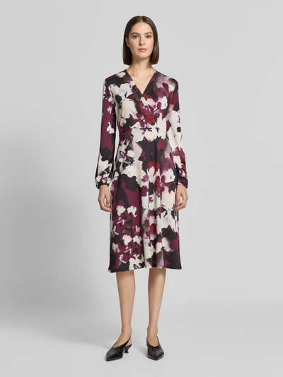 Frauenmodel trägt Midikleid in Wickel-Optik mit V-Ausschnitt von ZABAIONE, Allover-Look in Creme, Rot und Schwarz, Ganzkörperansicht von vorne. Material-Mix mit Stretch-Anteil, A-Linie, Rückenlänge 112 cm, Brustweite 46 cm, Ärmellänge 62 cm.