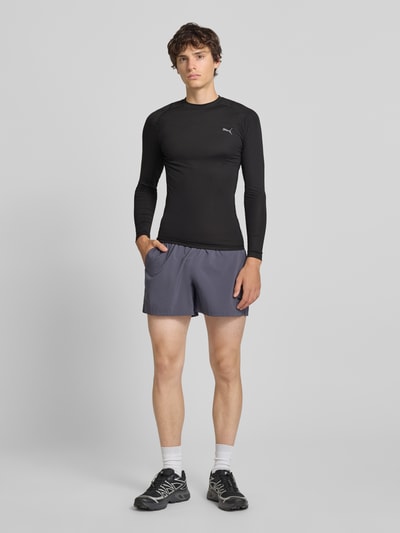 Männermodel trägt schwarzes Slim Fit Sport-T-Shirt mit Logo-Print Modell 'PWRMODE' von PUMA Performance, Ganzkörperansicht von vorne.