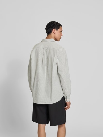 Männermodel trägt Relaxed Fit Freizeithemd mit Brusttasche von Forét aus reiner Baumwolle, hell mit feinen Streifen, Rückenansicht, Ganzkörperansicht Rückansicht.