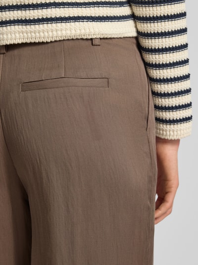 Frauenmodel trägt Regular Fit Stoffhose aus Lyocell-Mix mit Viskose-Anteil von Fynch-Hatton, hellbraun, feine Struktur, Detailaufnahme Gesäß. Bundfalten, Logo-Detail und Gesäßtaschen sichtbar, Bundweite 40 cm, Innenbeinlänge 78 cm.
