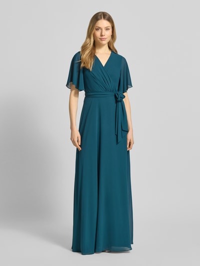 Vrouwenmodel draagt Regular Fit avondjurk met V-hals van Christian Berg Cocktail, taillerend, wikkel-look, afneembare stoffen riem, volledig bedekte rok, korte mouwen, kleur teal, licht glanzende textuur, voorkant volledig zichtbaar, volledige lichaamsweergave.