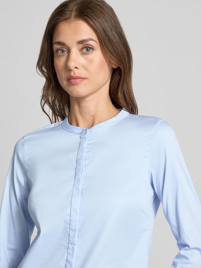 Modelka nosi bluzkę z mieszanki bawełny z dodatkiem streczu MOS MOSH Bluse mit Mao-Kragen und Rüschenärmeln Modell 'Mattie', prosta forma, stójka, ukryta listwa guzikowa, rękawy z falbanami, długość tyłu w rozmiarze S: 63 cm, długość rękawów w rozmiarze S: 62 cm, jasnoniebieska, gładka faktura, zbliżenie górnej części ciała, widok z przodu.