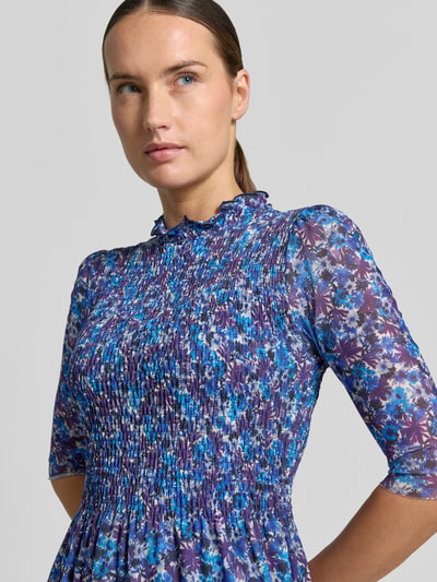 Kobiece modelka nosi sukienkę midi z marszczonym detalem od Rich & Royal, elastyczna mieszanka materiałów, taliowany krój, stójka z obszyciem falbanami, rękaw o dł. 1/2, kwiatowy nadruk na całej powierzchni, zbliżenie na górną część ciała