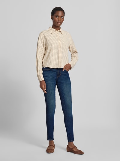 Vrouwenmodel draagt Slim Fit Jeans uit katoenmix Model 'Curve' van GUESS met 5-pocketmodel, knoop- en ritssluiting, blauw, Ganzkörperansicht van voren. Context: Dames jeans van GUESS, elastische katoenmix, slim fit, model 'Curve', 5-pocketmodel, knoop- en ritssluiting, bandwijdte bij maat 27/30: 37 cm, binnenbeenlengte bij maat 27/30: 78 cm.