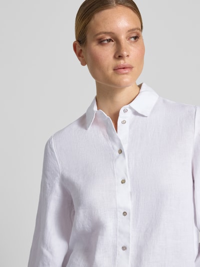 Frauenmodel trägt Relaxed Fit Leinenbluse mit 3/4-Arm von Christian Berg Woman aus weißem Leinen mit Knopfleiste und Hemdblusenkragen, Nahaufnahme Oberkörper. Rückenlänge bei Größe 36: 65 cm, Ärmellänge: 48 cm.