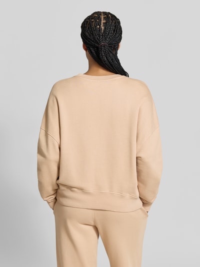 Frauenmodel trägt Oversized Sweatshirt aus Baumwoll-Mix von Juvia in Beige, mit Fleece-Innenseite und gerippten Abschlüssen, Ganzkörperansicht Rückansicht.