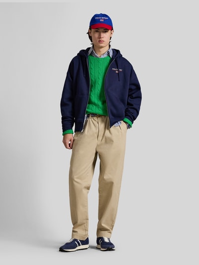 Männermodel trägt Relaxed Fit Sweatjacke aus Baumwoll-Mix von Polo Ralph Lauren in Dunkelblau, unifarben, mit Reißverschluss und Kapuze, Ganzkörperansicht von vorne.
