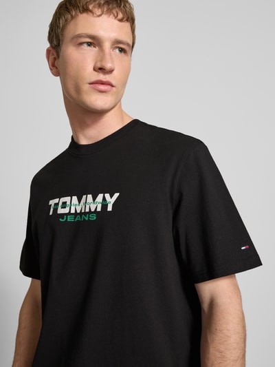 Männermodel trägt Regular Fit T-Shirt aus reiner Baumwolle von Tommy Jeans, Optik: Unifarben, Label-Schriftzug, Rundhals, Kurzarm, Materialverarbeitung: Webware, Nahaufnahme Oberkörper.