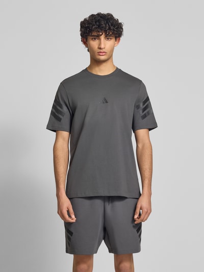 Männermodel trägt Relaxed Fit T-Shirt aus reiner Baumwolle von adidas Sportswear, Optik: Unifarben, Logo-Print, Ganzkörperansicht von vorne.