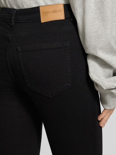 Kobieta modelka nosi Slim Fit Jeans im 5-Pocket-Design od REVIEW, elastyczna mieszanka bawełny, czarna, detal z tyłu, zbliżenie na biodra.