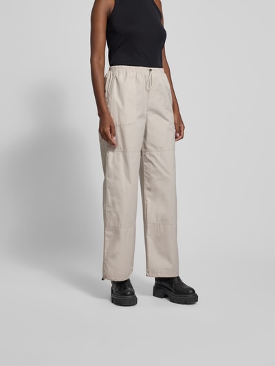 Frauenmodel trägt Stoffhose mit elastischem Bund von black palms aus reiner Baumwolle, lockerem Schnitt, Tunnelzug, Eingrifftaschen, Ganzkörperansicht von vorne.
