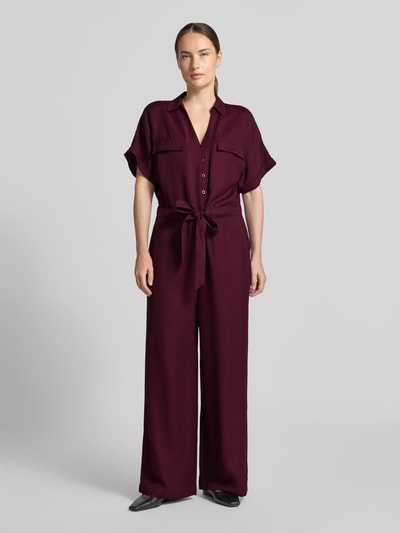 Frauenmodel trägt Jumpsuit aus Viskose-Lyocell-Mix von MORE & MORE in Dunkelrot, glatte Textur, taillierte Passform, Ganzkörperansicht von vorne.