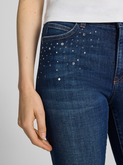 Frauenmodel trägt Skinny Fit Jeans aus elastischem Baumwoll-Mix mit Strasssteinen von Marc Cain, 5-Pocket-Design, Nahaufnahme Oberkörper.
