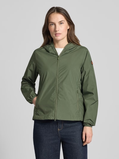 Modelka kobieca nosi Regular Fit Jacke mit Zweiwegereißverschluss Modell 'Stella' od SAVE THE DUCK, zieleń, prosty krój, gładka struktura, dwukierunkowy zamek, kieszenie na zamek, długość tyłu 60 cm, szerokość ramion 42 cm, szerokość w rozmiarze S 52 cm, długość rękawa 64 cm; widok na cały przód.