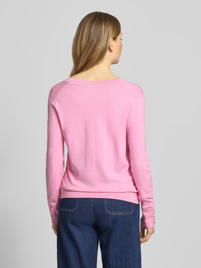 Vrouwenmodel draagt Regular Fit Strickpullover aus reiner Baumwolle van Tommy Hilfiger in effen roze, lange mouw, rompzoom geribd, gestikt logo, tricot, puur katoen, gebreid, sierknopen, all-over motief, gestreepte look, gebreide structuur, ganzkörperaanzicht achteraan.
