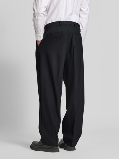 Männermodel trägt Straight Fit Stoffhose mit Bundfalten von ANNARR in Schwarz, Eingrifftaschen, Leistentaschen am Gesäß, Ganzkörperansicht Rückansicht.