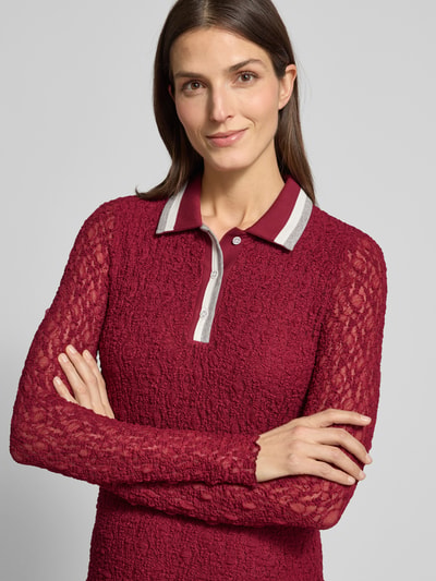 Frauenmodel trägt Slim Fit Kleid mit Polokragen von Marc Cain, langärmelig, bordeauxrot, Spitzenstruktur, Nahaufnahme Oberkörper.