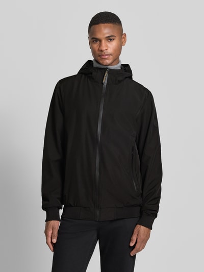 Männermodel trägt Jacke mit Reißverschlusstaschen Modell 'MATTEO' von CARS JEANS, schwarzer Material-Mix mit Stretch-Anteil, Regular-Fit, Kapuze, Ganzkörperansicht von vorne.