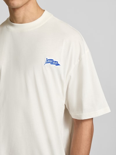 Męski model nosi Oversized T-Shirt aus reiner Baumwolle Modell 'Nohatio' von HUGO, jednokolorowy, z aplikacją z metką, okrągły dekolt, krótki rękaw, wykonanie z dżerseju, bawełna, zbliżenie na górę ciała.