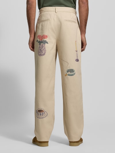 Männermodel trägt Stoffhose mit Motiv-Prints Modell 'Romeo' von Les Deux, beigefarbener Stoff, lockerer Schnitt, Ganzkörperansicht Rückansicht.