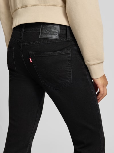 Männermodel trägt schwarze Slim Fit Jeans aus Baumwoll-Lyocell-Mix Modell '511® SLIM' von Levi's®, Herren Slim Fit Jeans, Ganzkörperansicht Rückansicht.