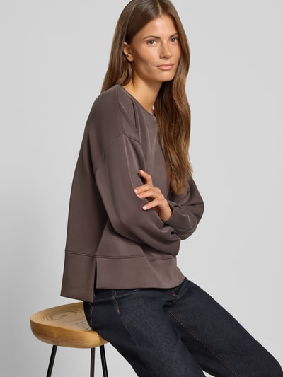 Vrouwenmodel draagt sweatshirt met viscose van comma in taupe, losse pasvorm, ronde hals, elastische band, Materiaalmix, zijaanzicht, heuphoogte.