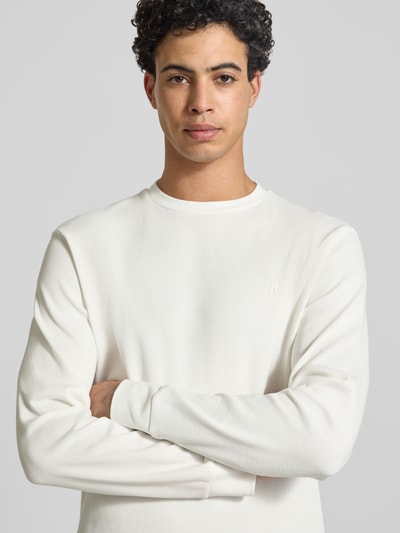 Męski model nosi Bluza 'Sweatshirt mit Stehkragen' od Replay z bawełny, prosty krój, stójka, faktura wafla, detal z logo, elastyczne zakończenia rękawów, długość tyłu 63 cm, długość rękawów 67 cm, widok na górną część ciała z przodu.